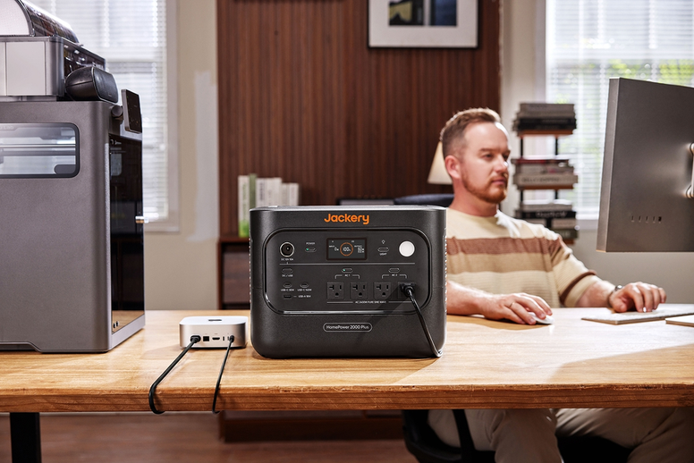 Jackery HomePower 2000 Plus portable power station connected to a compact device on a home office desk