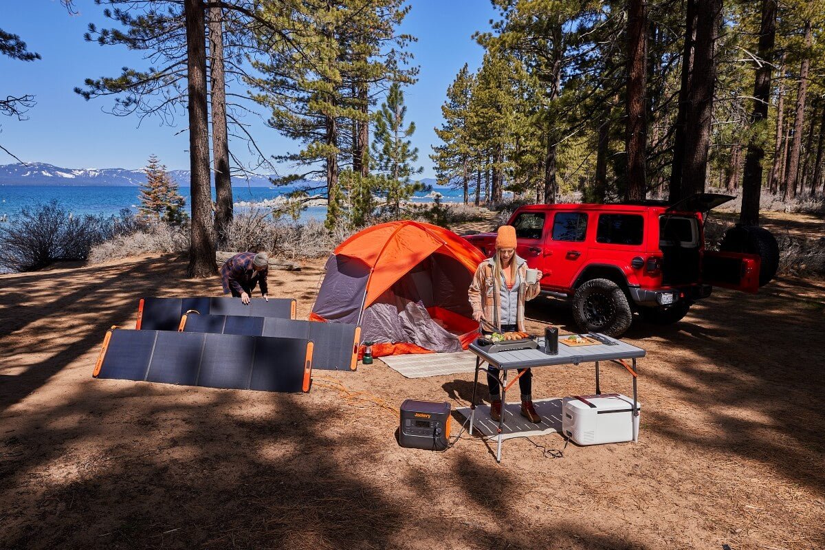 Outdoor camping setup with portable solar panels and power station by the lake.