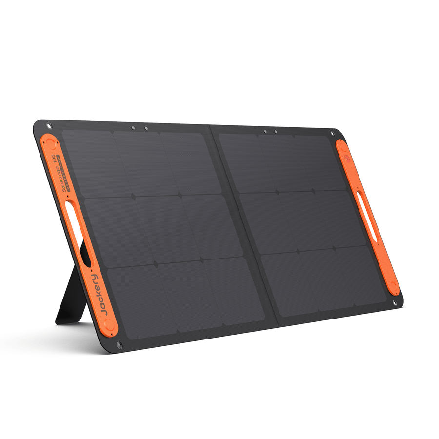 Jackery SolarSaga 100W portable solar panel, two-segment rigid-frame monocrystalline unit unfolded on its integrated rear kickstand, with the orange-trimmed border, Jackery branding along one edge, and cutout carry handles on both side frames.